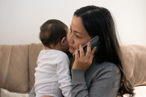 young mother holding with infant with fever calling