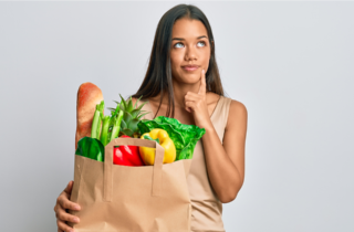 woman with shopping bag full of healthy food looks to be thinking