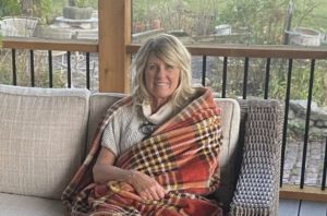 Misty Barnes sits on a patio with a blanket.