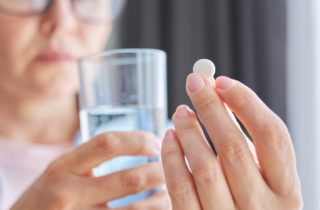 woman holding menopause supplements and a glass of water in her hand.