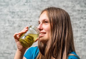 girl drinking pickle juice from a jar.